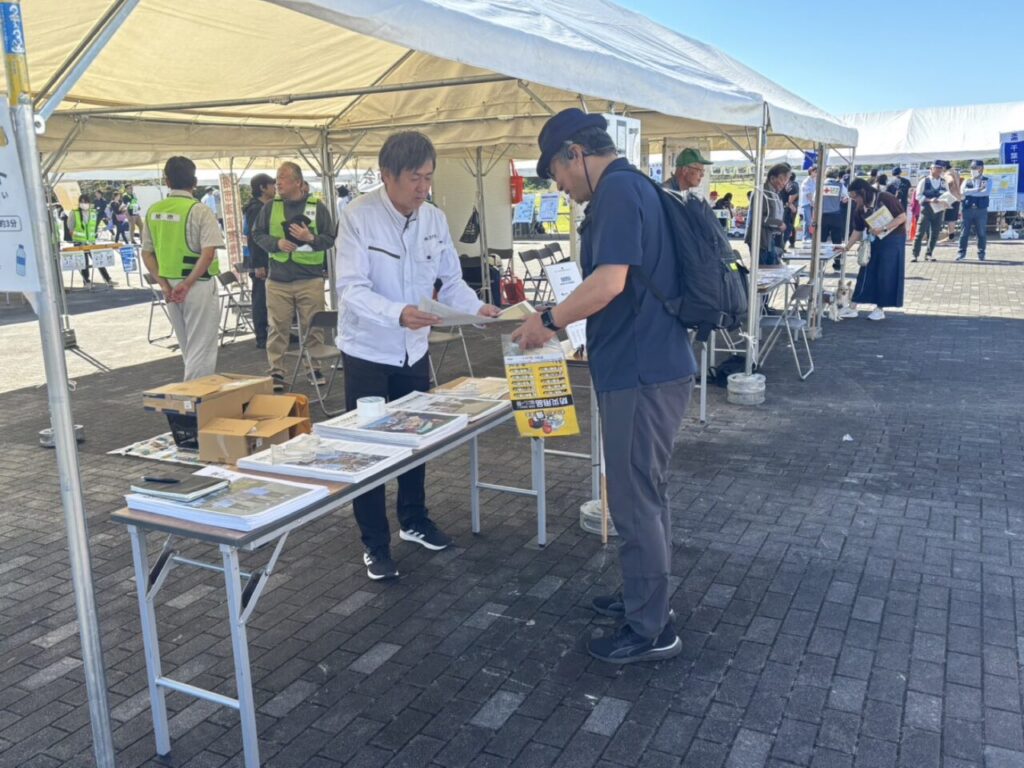 ブースで新聞をお渡ししながらお話ししているところ